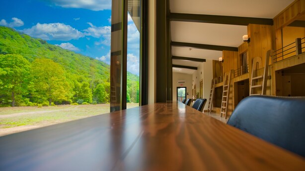 A conference room with a large table, wooden walls, and a view of a green landscape. - Stunning Modern Private Cabin at River Mountain Resort (Everett)