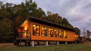 A wooden cabin with a deck, large windows, and a staircase leading to the upper level. - Stunning Modern Private Cabin at River Mountain Resort (Everett)