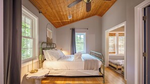 A bedroom with a bed, bedside table, and a ceiling fan. - Hygge Blue Chalet ~ 2 Large Suites, Sleeps 8, Hot Tub, Convenient, 2 balconies (Sevierville)