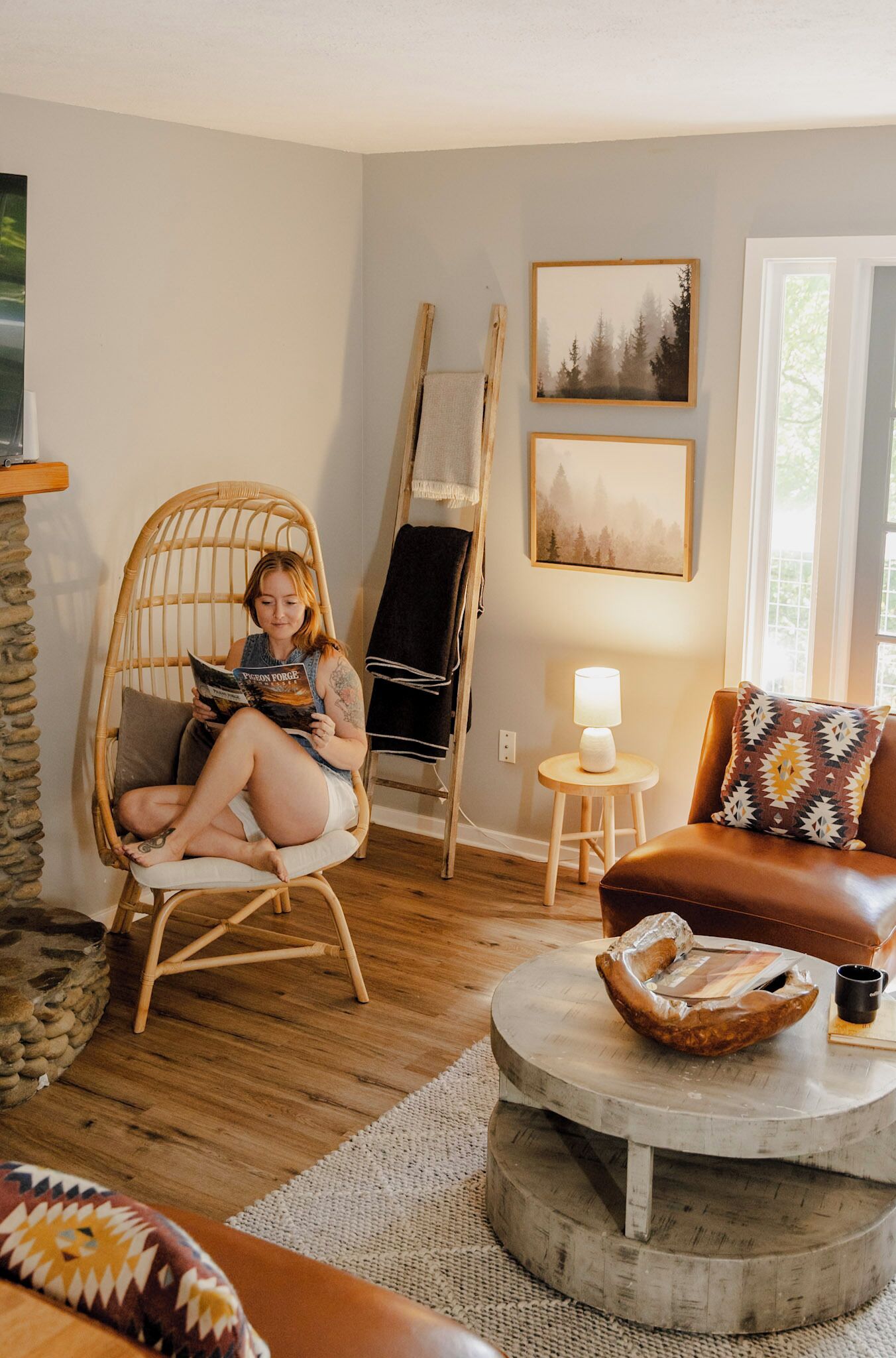 A cozy living room with a wicker chair, a round coffee table, and a brown leather sofa.