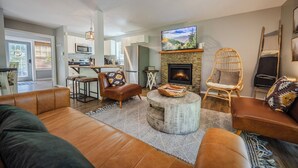 A modern living room with a fireplace, leather sofas, and a stone coffee table. - Hygge Blue Chalet ~ 2 Large Suites, Sleeps 8, Hot Tub, Convenient, 2 balconies (Sevierville)