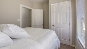 A bedroom with a bed, two doors, and a window with blinds. - WL1- Modern 2BR Retreat Minutes from Downtown & Top SA Attractions (San Antonio)