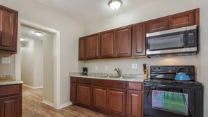 A kitchen with wooden cabinets, a microwave, a stove, and a coffee maker. - WL1- Modern 2BR Retreat Minutes from Downtown & Top SA Attractions (San Antonio)