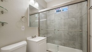 A bathroom with a glass-enclosed shower, a white sink, and a toilet. - WL1- Modern 2BR Retreat Minutes from Downtown & Top SA Attractions (San Antonio)