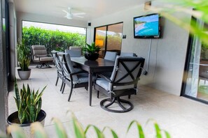Un comedor moderno con una mesa y sillas, un televisor en la pared y plantas en macetas.