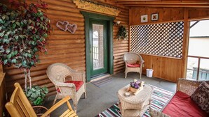 A log cabin interior with wicker furniture, a green door, and a lattice wall. - Encanto Lodge - Downtown Chama 1 Block From Train (Chama)