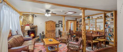 A cozy living room with a fireplace, leather sofa, wooden furniture, and a bookshelf.