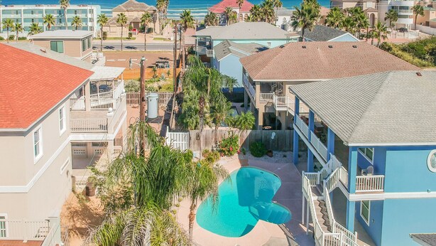 Un quartier résidentiel doté d’une piscine, entouré de maisons et de palmiers.