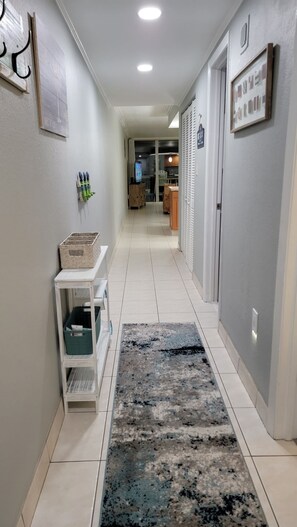 Enter a spacious hallway with a comfortable rug, a shelf unit, and a small table.