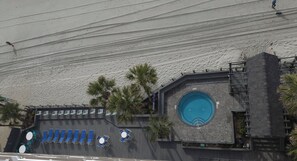 A building with a swimming pool, lounge chairs, and palm trees. - Water's Edge Resort 10th Floor (Murrells Inlet)