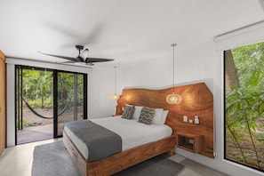 A bedroom with a large bed, a ceiling fan, and a view of the outdoors through a sliding door.