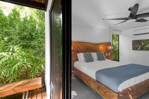 A bedroom with a bed, a ceiling fan, and a view of greenery outside.