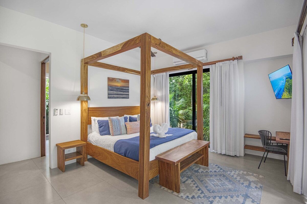 A bedroom with a four-poster bed, a desk, and a chair.