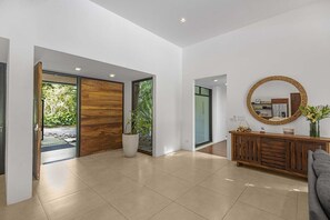 Ein modernes Interieur mit einer Holztür, einem großen Spiegel und einem Konsolentisch.
