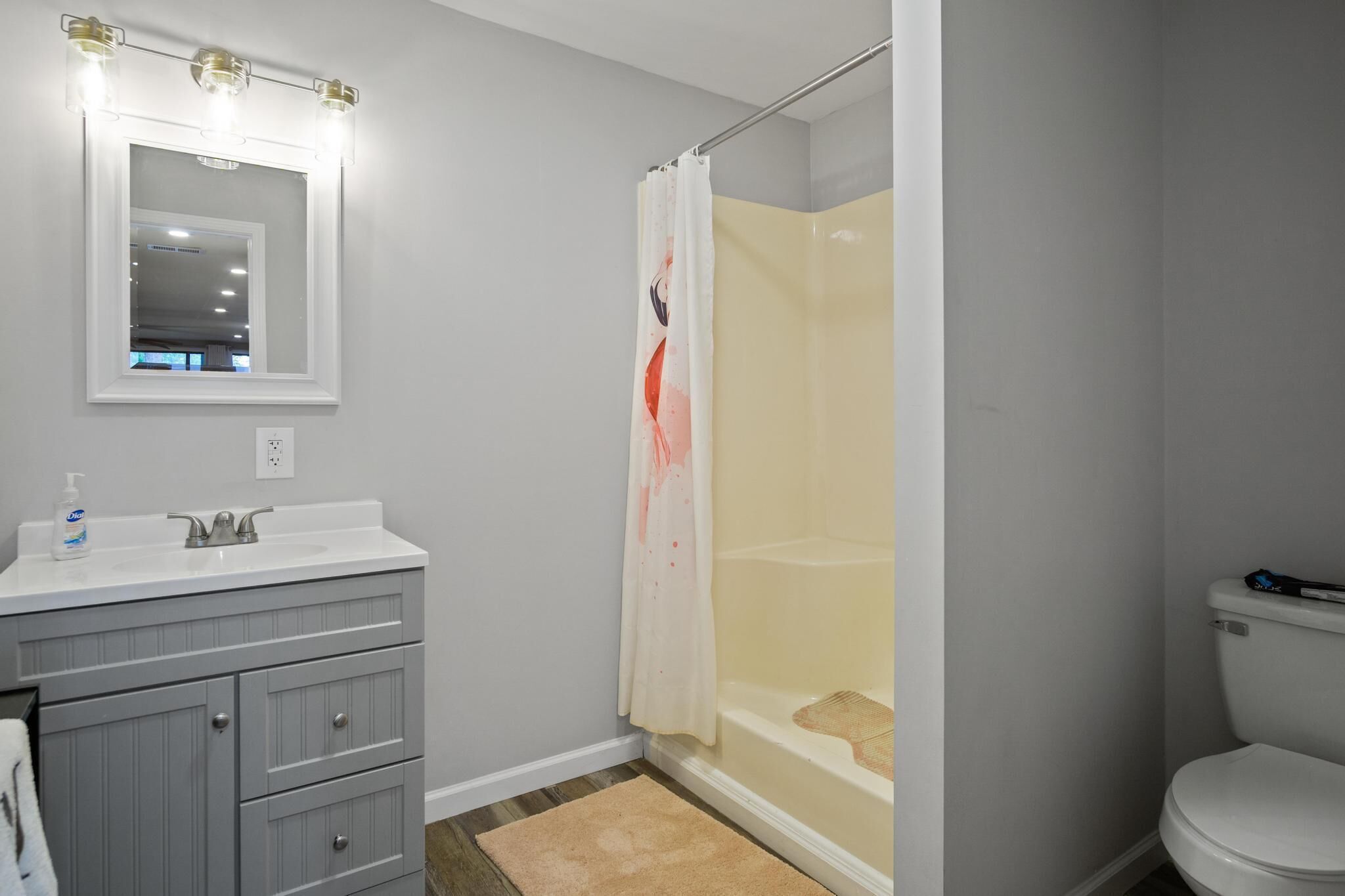 A bathroom with a vanity, sink, mirror, and shower curtain.