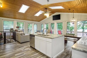 Enjoy cooking in this well-equipped kitchen with a large island, sink, and dishwasher, offering stunning views of the surrounding greenery.
