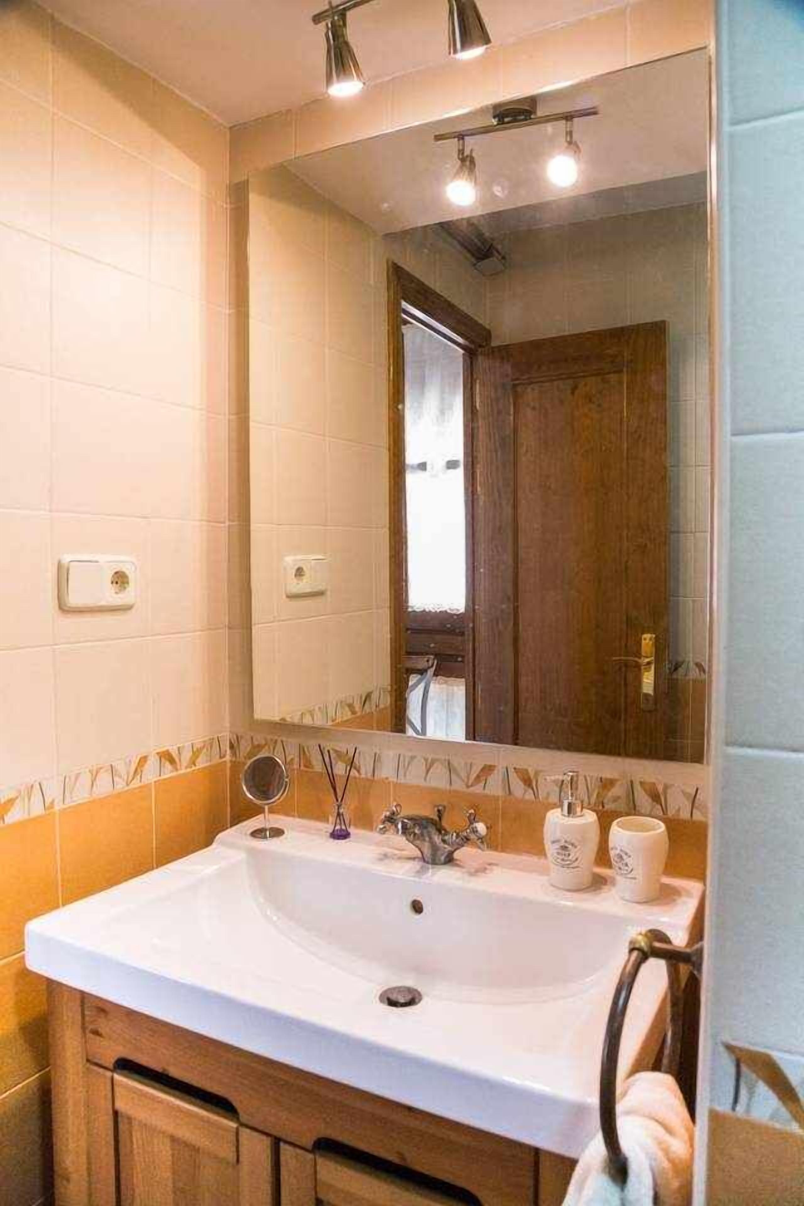 Bany amb un gran mànec, mirall i armari de fusta.