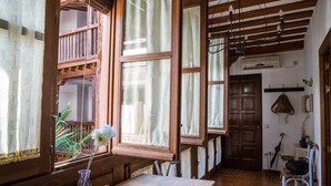 Habitación rústica con vigas de madera, una mesa de madera y una ventana con cortinas.