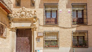 A historic building with a large ornate door, multiple balconies with iron railings, and potted plants. - Apartamento San Vicente by Toledo AP (Toledo)