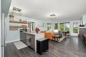 Una cocina moderna con una isla central, electrodomésticos integrados y un comedor con un amplio ventanal.