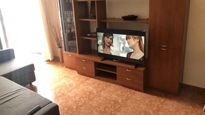 Una sala de estar con una unidad de entretenimiento de madera, un televisor y un sofá.