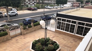Un patio con una jardinera, vista a la calle y un edificio con grandes ventanales.