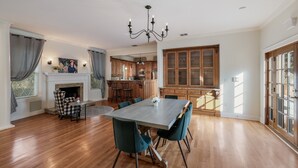 Ein geräumiger Essbereich mit großem Tisch und Stühlen, einem Kamin und einer Küche im Hintergrund.