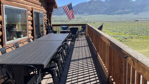 Eine Holzhütte mit Terrasse, Sitzgelegenheiten im Freien und Blick auf die Berge.