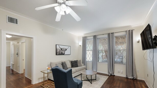A living room with a sofa, armchair, coffee table, and a ceiling fan.