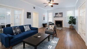Un salon spacieux avec un canapé bleu, une table basse, une cheminée et un ventilateur de plafond.