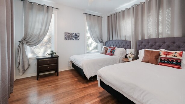 Une chambre avec deux lits, un ventilateur de plafond et une table de chevet.