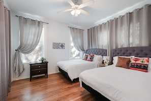 A bedroom with two beds, a ceiling fan, and a nightstand.