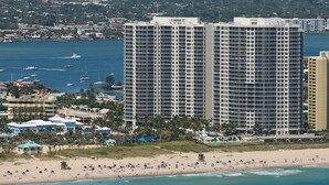 A high-rise hotel with multiple floors, a beach in the foreground, and boats in the water. - Luxury Condo in the Ritz Carlton Residences on a private beach  (Riviera Beach)