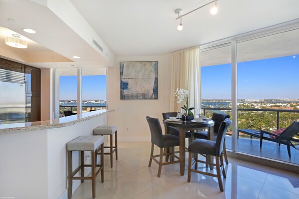 A modern dining area with a view of the cityscape. - Luxury Condo in the Ritz Carlton Residences on a private beach (Riviera Beach)