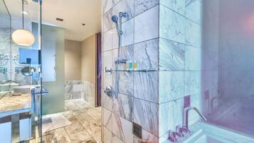 A modern bathroom with marble tiles, a glass shower enclosure, and a vanity with a mirror.