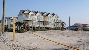 A beachfront hotel with multiple balconies, sandy beach in front, and a clear sky. - Ocean View, steps from sand, enjoy it all in your spacious 3-bedroom retreat (Surf City)