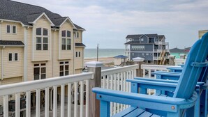 A beachfront property with a wooden deck and blue chairs, overlooking the ocean and beach. - Ocean View, steps from sand, enjoy it all in your spacious 3-bedroom retreat (Surf City)