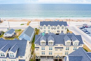Un quartier résidentiel situé sur la côte, composé de plusieurs maisons à deux étages, d’une plage et d’un parking.