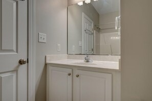 Une salle de bain avec un meuble-lavabo blanc, un miroir et un espace douche.