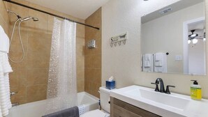 Casa de banho com chuveiro, sanita, lavatório e toucador.