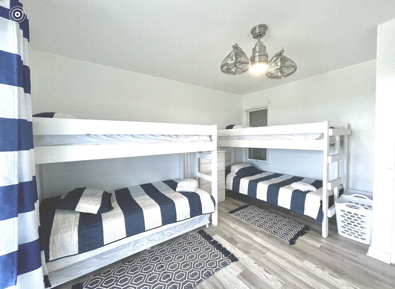 Ein Zimmer mit Etagenbetten, einem gemusterten Teppich und einer Pendelleuchte.