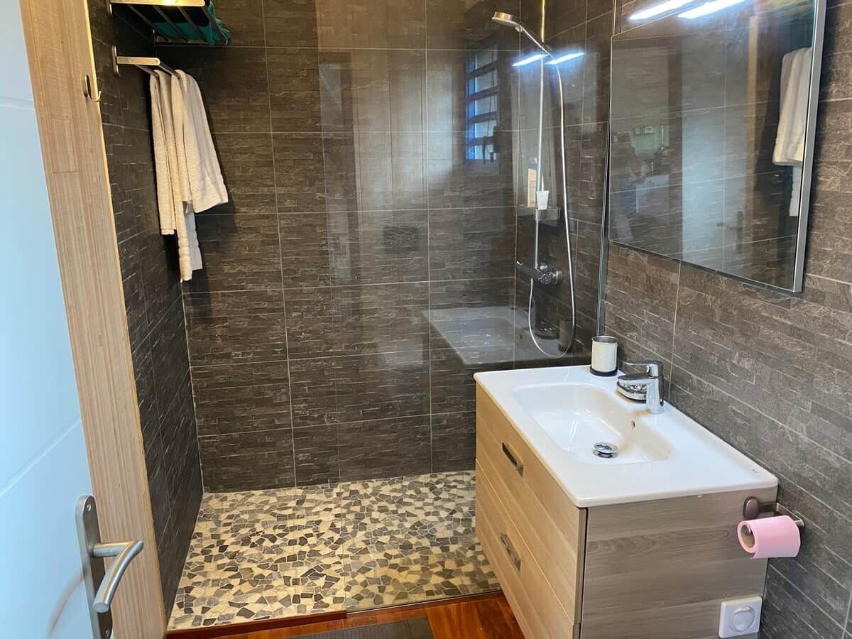 A bathroom with a shower, a sink, and a mirror.