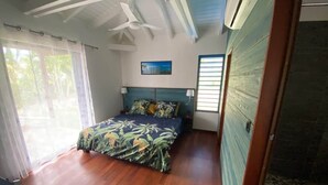 A bedroom with a bed, a ceiling fan, and a window.