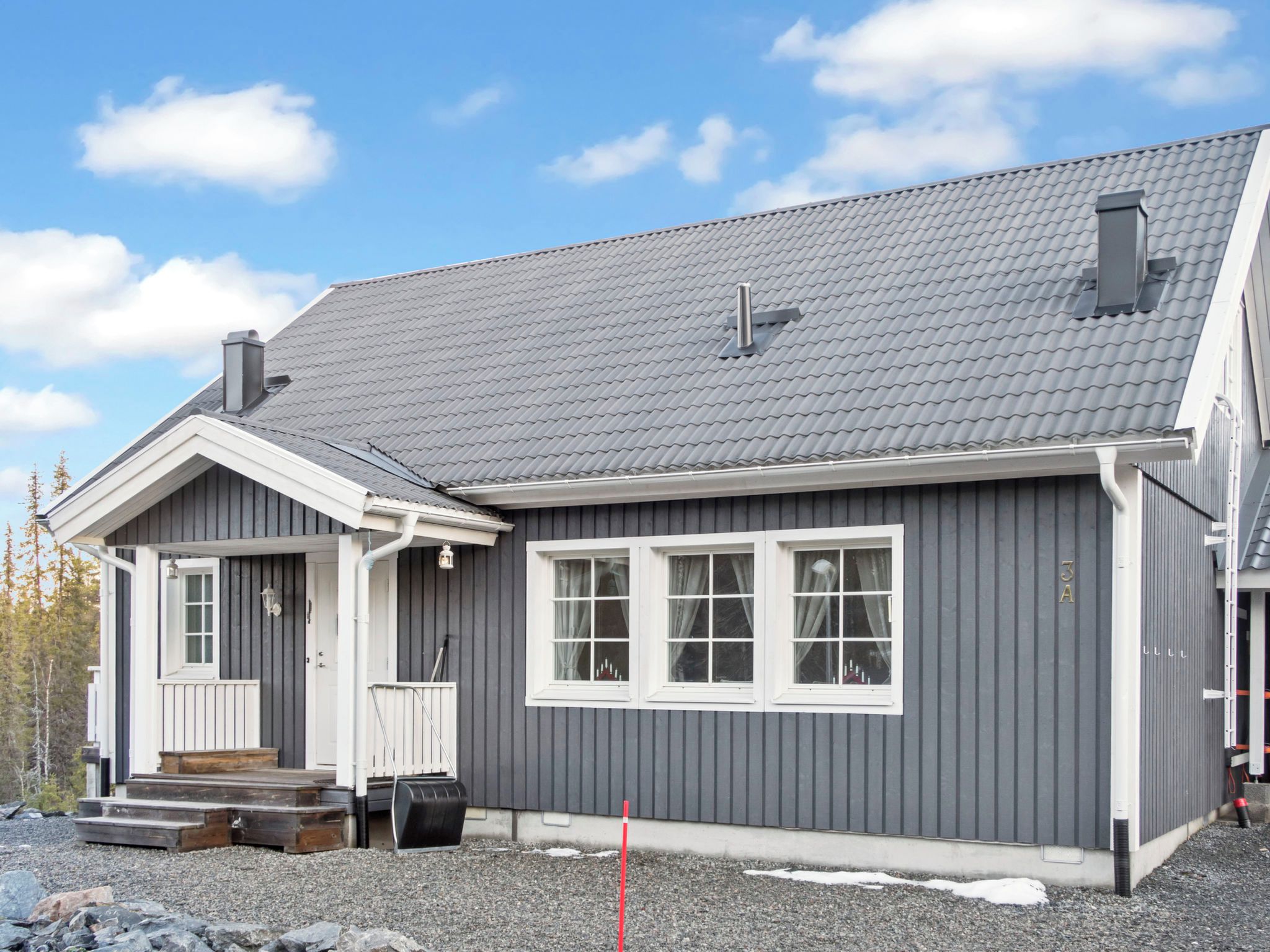 A two-story house with a grey exterior, white trim, and a grey tiled roof.