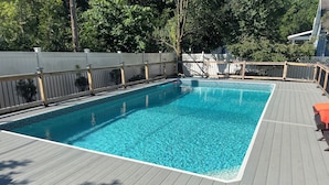 Ein rechteckiger Pool mit einer ihn umgebenden Holzterrasse.