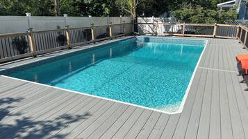 A rectangular swimming pool with a wooden deck surrounding it.