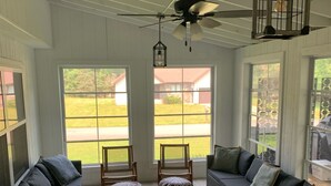Ein geräumiges Zimmer mit großem Fenster, Deckenventilator und Rattansitzgruppe.
