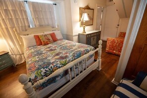 A bedroom with a bed, a dresser, a chair, and a window with curtains.