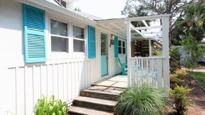 Een wit huis met turquoise luiken en een overdekte veranda.