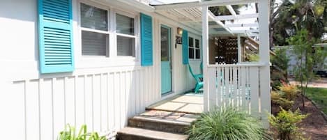 A white house with turquoise shutters and a covered porch.